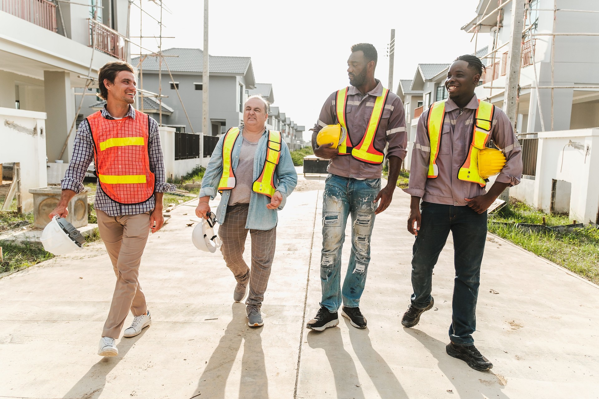Group of construction workers walking confidently on-site, discussing progress in a residential housing project. Symbol of teamwork, safety, and collaboration in the real estate industry.